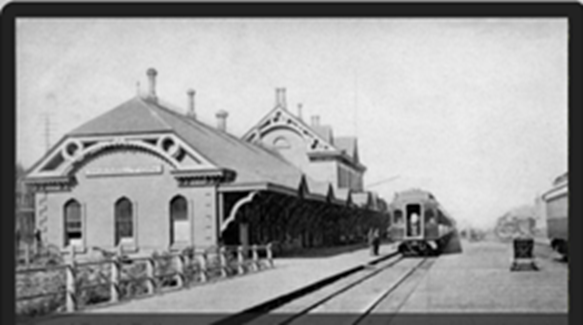 A black and white photo of the GTR Railway station in Hamilton (ca. 1903) with a train waiting.