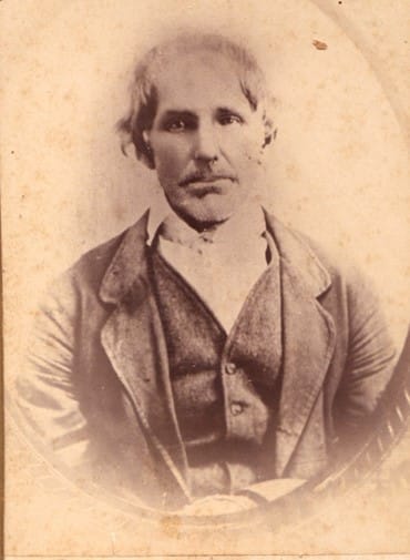 Portrait of a man in vest, jacket, shirt and collar, but no tie.
