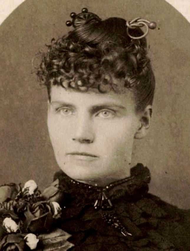 A headshot photograph of a well-dressed woman with upstyled hair.