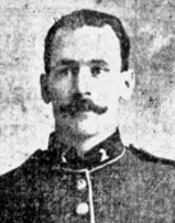 A headshot photo of a mustached soldier in 19th century regimental uniform.